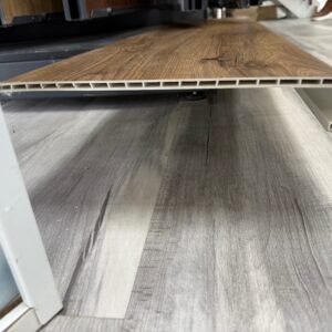 Close-up of a wood-look laminate plank showing its hollow-core, grid-like internal structure and edge cap.